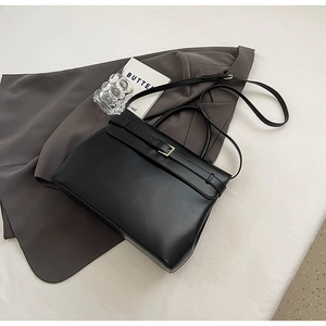 Detail of minimalist black leather briefcase with gold hardware and detachable strap