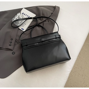 Detail of elegant black leather briefcase on a blazer with refined office accessories