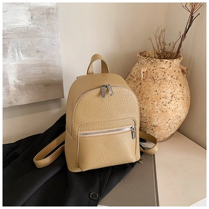 Detail of khaki pebbled leather mini backpack with silver zipper on black clothing