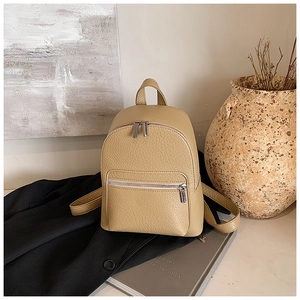 Detailed close-up of beige lychee grain leather mini backpack in a vintage lifestyle setting