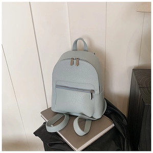 Close-up of light blue leather backpack with litchi grain texture and silver zippers