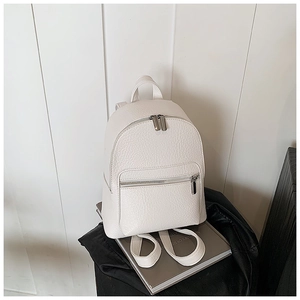 Detail shot of white pebbled leather mini backpack with silver zippers and top handle