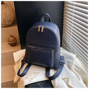 Detail of navy pebble leather backpack with silver zippers in a minimalist scene