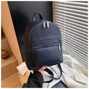 Detail of navy blue pebble leather backpack featuring silver zippers and front pocket