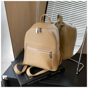 Close-up of beige pebbled leather backpack with silver zippers and minimalist design
