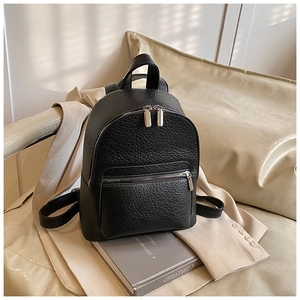Detail of black pebbled leather texture and polished silver zippers on fashion backpack