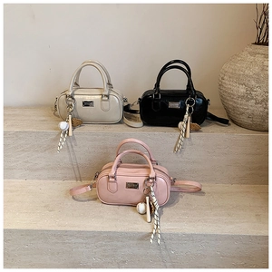 Three leather bowling bags in cream, black and pink with sporty ball charms on stone steps