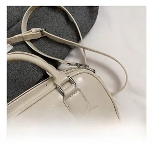 Detail showing the creamy beige pleated leather texture and silver metal hardware of the bag
