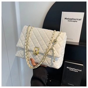 Detail of white quilted handbag featuring gold metal chain and rectangular twist lock