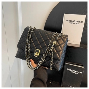 Detail of black quilted leather bag featuring a gold chain strap and rectangular turn-lock