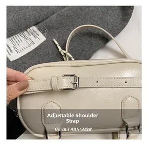 Detail of adjustable shoulder strap with silver buckle on cream bowling handbag