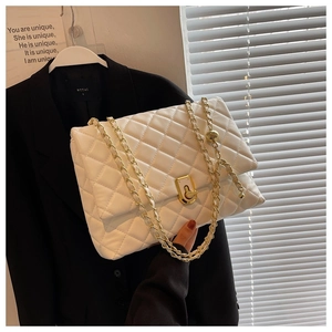Close-up of white quilted leather texture with gold metal chain and turn-lock buckle detail