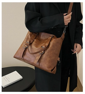 Detail of vintage brown leather tote bag with subtle texture and dark metal rings