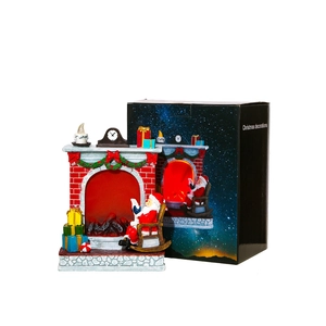 Christmas resin fireplace ornament with Santa reading by a glowing fire in a gift box