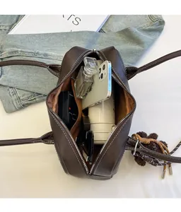 Spacious interior of deep brown baguette bag holding a phone, perfume, and cosmetics