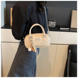 Detail of a beige PU leather bowling bag with twin handles and a baseball bag charm