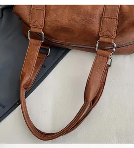 Detail of brown lychee leather texture and silver square metal buckle on travel tote bag