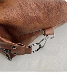 Close-up of gunmetal hardware hooks on a dark brown litchi pattern leather tote bag