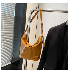 Close-up of caramel oil-wax leather texture with adjustable strap and gold buckle