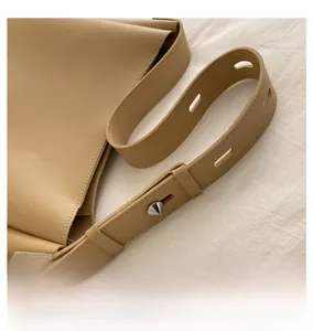 Detail of adjustable wide shoulder strap with silver metallic studs on khaki PU tote bag