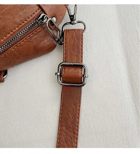 Detail of metal strap adjustment buckle on brown pebble grain leather travel tote bag