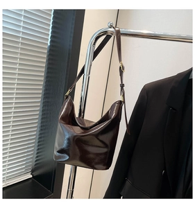 Detail of dark brown leather hobo bag with adjustable strap and golden hardware