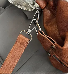 Detailed macro view of high-quality silver metal swivel hook on brown leather tote bag