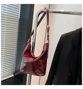 Detail view of burgundy hobo bag with glossy leather texture and gold hardware