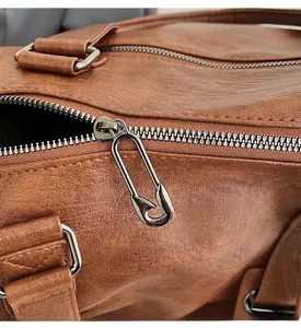 Detail of lychee textured leather and unique safety pin metal zipper on brown tote bag