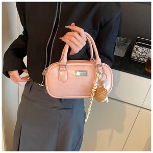 Detailed shot of pink patent leather bowling bag with silver plaque and charm accessory