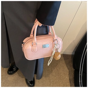 Detail of light pink bowling bag with metallic logo and textured synthetic leather