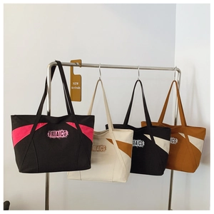 Detail of color-block canvas tote bags with FRIAICG print on a display stand