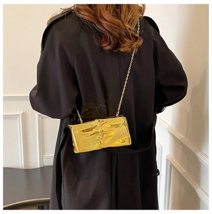 Vista posterior de modelo con bolso bandolera dorado metalizado con cadena fina