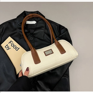 Close-up of the vintage cream and brown leather shoulder bag with silver logo plaque
