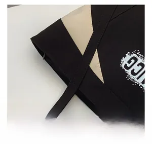 Detailed close-up of reinforced stitching on the black and beige canvas tote bag handle