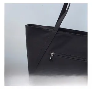 Detail of the smooth silver metal zipper on a large black canvas tote bag