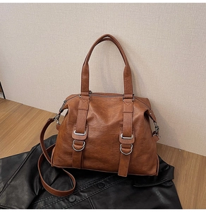 Close-up of brown vintage leather tote bag with silver hardware on a leather jacket