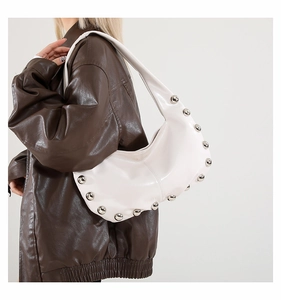 Detailed view of white crescent bag featuring polished rivets and high-quality faux leather