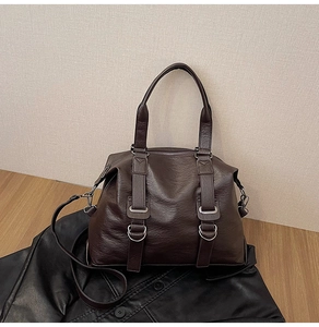 Detail of dark brown faux leather travel tote bag with silver rings and crossbody strap