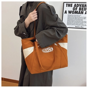 Detail of large canvas tote bag in orange and white color block with logo print