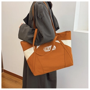 Detail view of large contrast tote bag in caramel and beige canvas with logo text