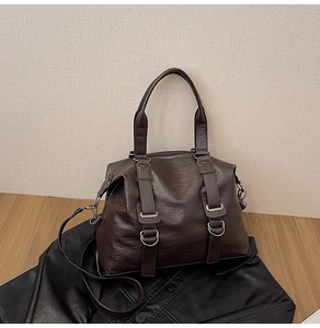 Detail of dark brown tote bag featuring textured faux leather and silver metal buckles