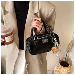 Close-up of black patent leather bowling bag with silver hardware and glove charm