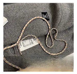 Détail du sac en cuir matelassé beige avec chaîne dorée posé sur un manteau gris