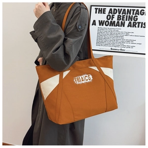 Detail of contrast canvas tote bag featuring white letter logo and long shoulder straps