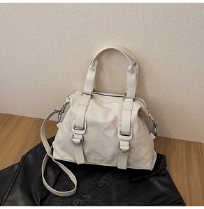 Detail of cream Boston bag with lychee texture, silver D-rings, and adjustable strap