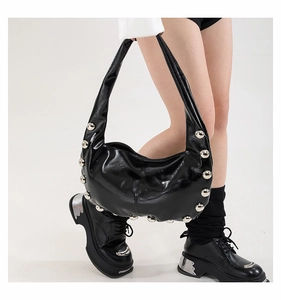 Detail shot of silver rivet studs on black leather hobo bag with glossy finish