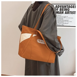 Detailed side view of large canvas tote bag showing two-tone geometric design and branding