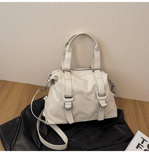Close-up of litchi grain cream leather travel bag with silver metal ring details