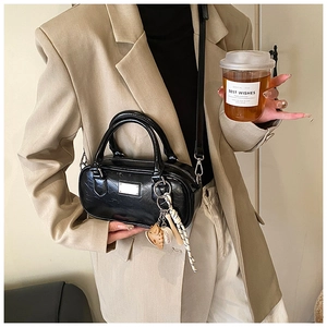 Fashionable black bowling bag with crinkled texture shown in a street style outfit